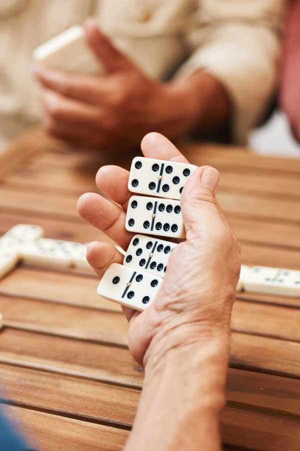 Hands holding dominos at Merrill Gardens at Renton Centre in Renton, Washington
